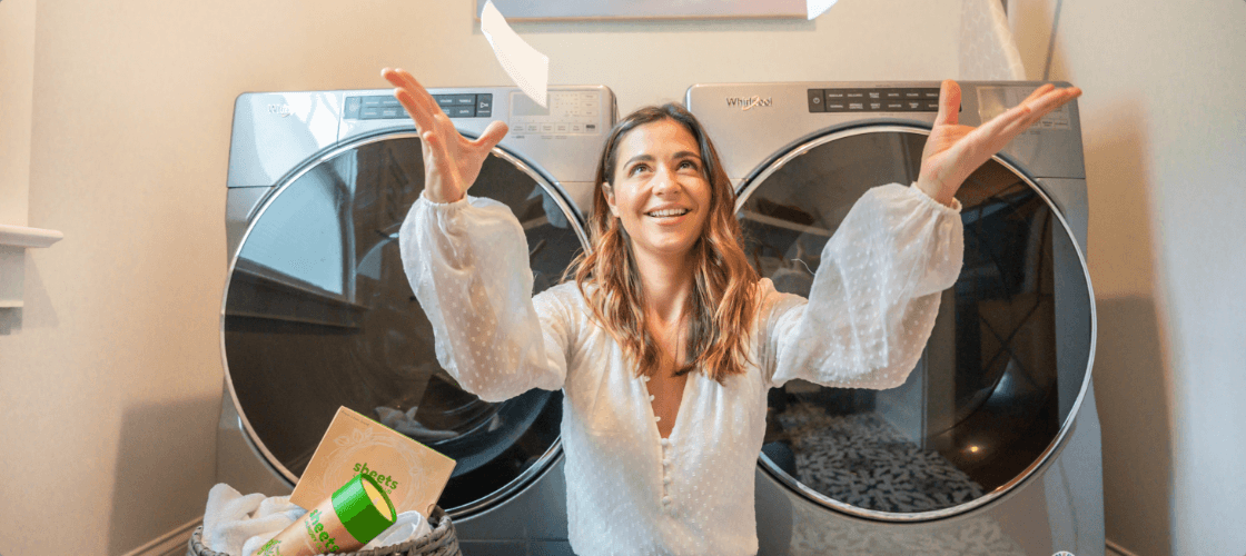 A woman throwing Laundry Detergent Sheets in front of a dryer